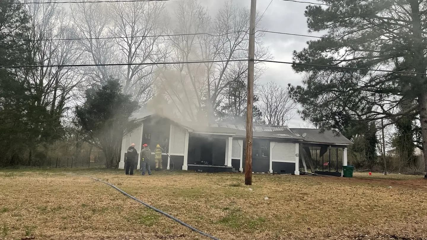Firefighters work a smoking single-family house fire from the front yard.