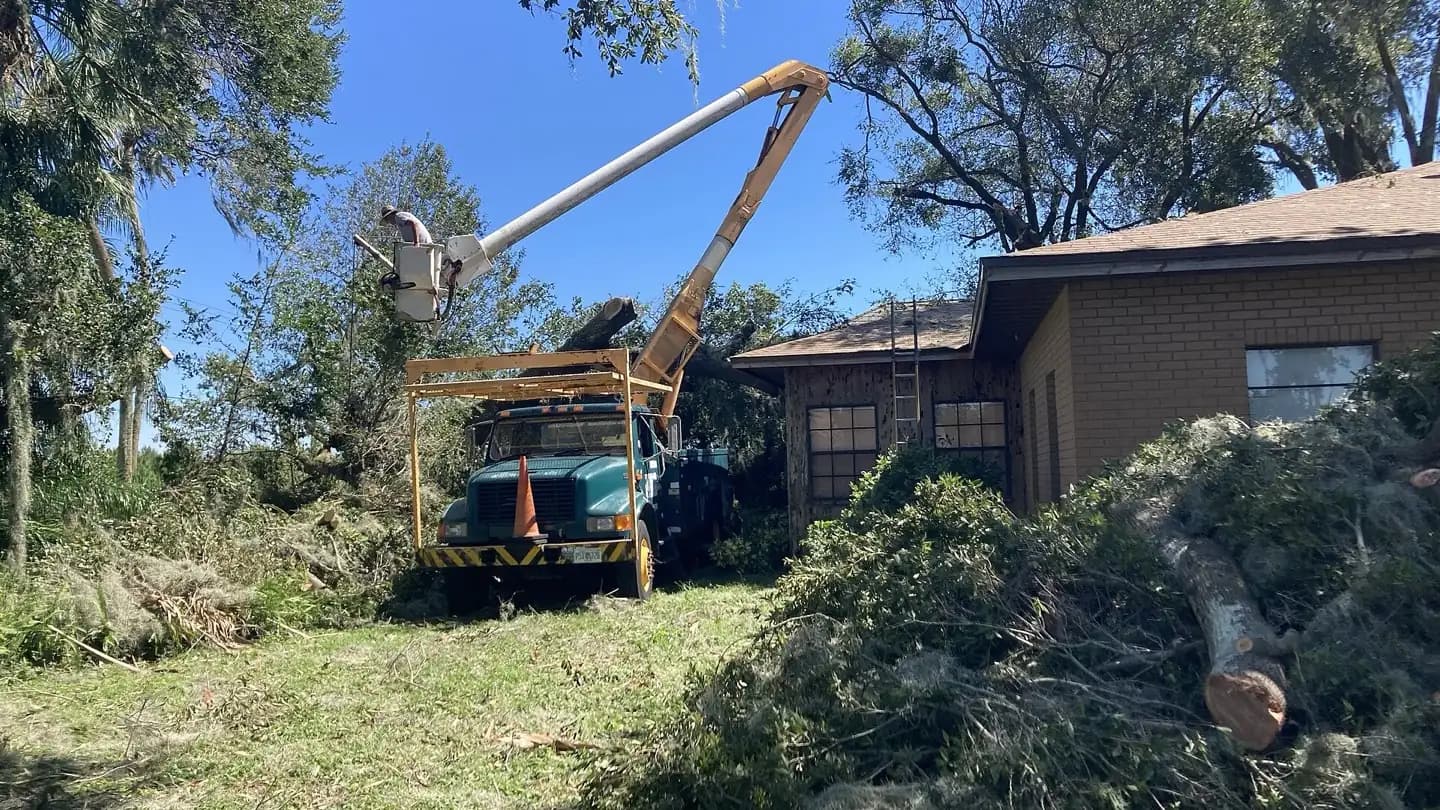 A bucket truck lifts a worker to clear a large tree that fell onto a Florida home after Hurricane Ian.