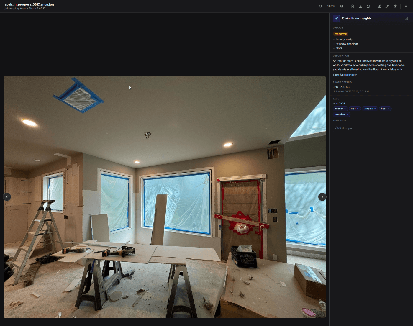 A claim photo open in claimOS with Claim Brain insights: moderate damage to interior walls, window openings and floor, a written description, and AI tags applied on upload.